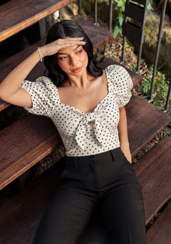 Esta blusa es de color blanco con un estampado de lunares negros.